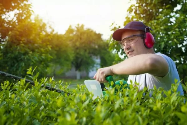 Giardiniere che usa un decespugliatore con occhiali protettivi